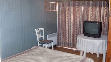 Una stanza con un letto, una sedia, una televisione su un tavolino e tende a fantasia.
