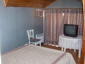 Een kamer met een bed, een stoel, een televisie op een bijzettafeltje en kamer met een patroon.