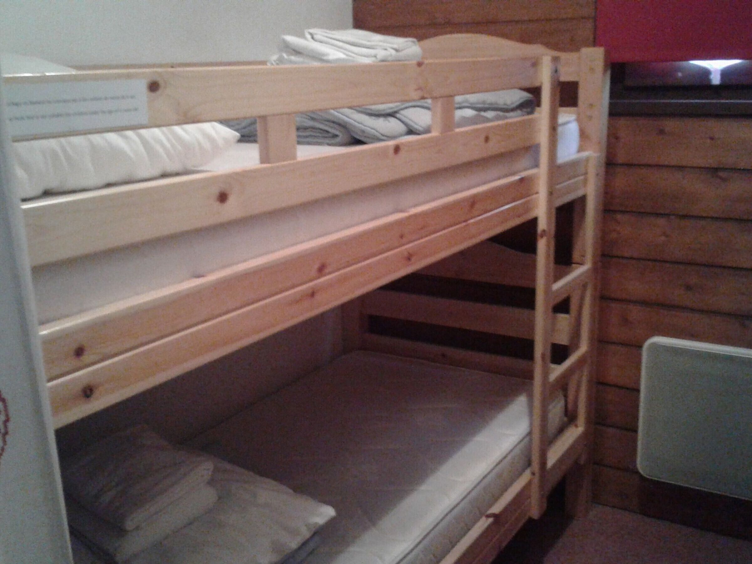 Un lit superposé avec une structure en bois, un matelas et des oreillers.