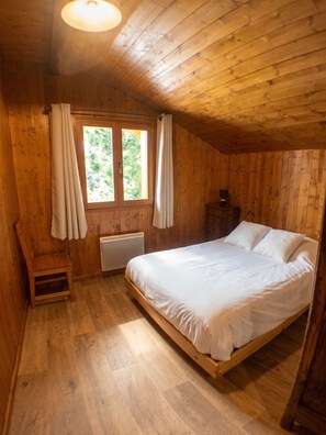 A wooden cabin bedroom with a single bed, a radiator, and a window with curtains. - Homerez - Chalet in Saint-Chaffrey, mountain view (Saint-Chaffrey)