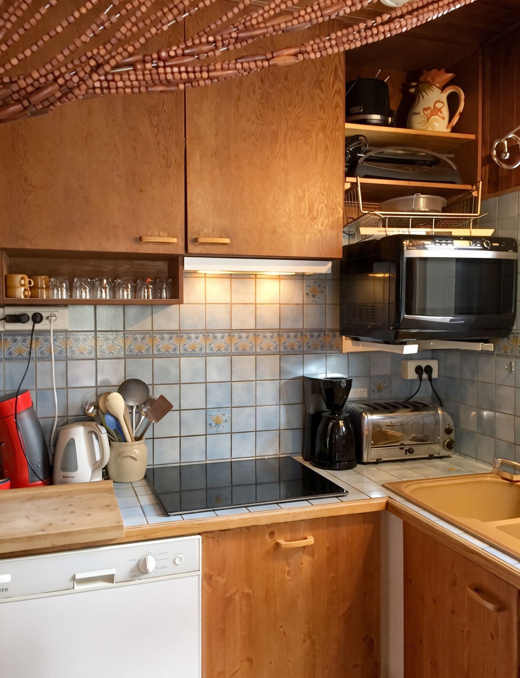 Une cuisine compacte dotée d’armoires en bois, d’un four à micro-ondes, d’un grille-pain et d’une machine à café.