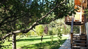 A wooden cabin with a balcony, surrounded by a grassy yard and trees. - Homerez - Chalet in Saint-Chaffrey, mountain view (Saint-Chaffrey)