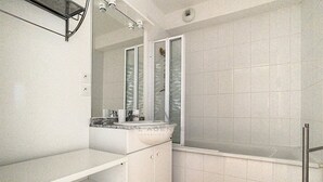 A modern bathroom with a white vanity, a large mirror, and a bathtub. - 2-bedroom apartment near sea and center, includes parking (Cucq-Stella Plage)