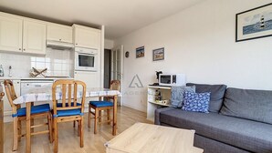 A compact living space with a dining area, kitchenette, and a grey sofa. - 2-bedroom apartment near sea and center, includes parking (Cucq-Stella Plage)