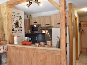 Una cocina con armarios de madera, un microondas, una estufa y un lavamanos. Hay elementos decorativos en la encimera y una pared con imágenes de plantas.