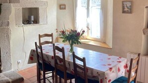 A dining area with a table set for four, a stone wall, and a window with a view.
