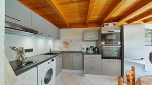 Une cuisine compacte équipée d’un lave-linge, d’une machine à café et d’un réfrigérateur.