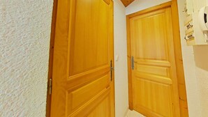Un couloir avec des portes en bois et un mur blanc à texture.