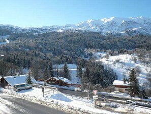 Un paysage montagneux enneigé avec une route, un chalet et un autobus.