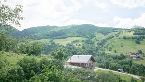 A rural house with a sloped roof, surrounded by lush green hills and a clear sky. - Renovated 7-room chalet in Valmorel, 15 people, parking, terrace (Valmorel)