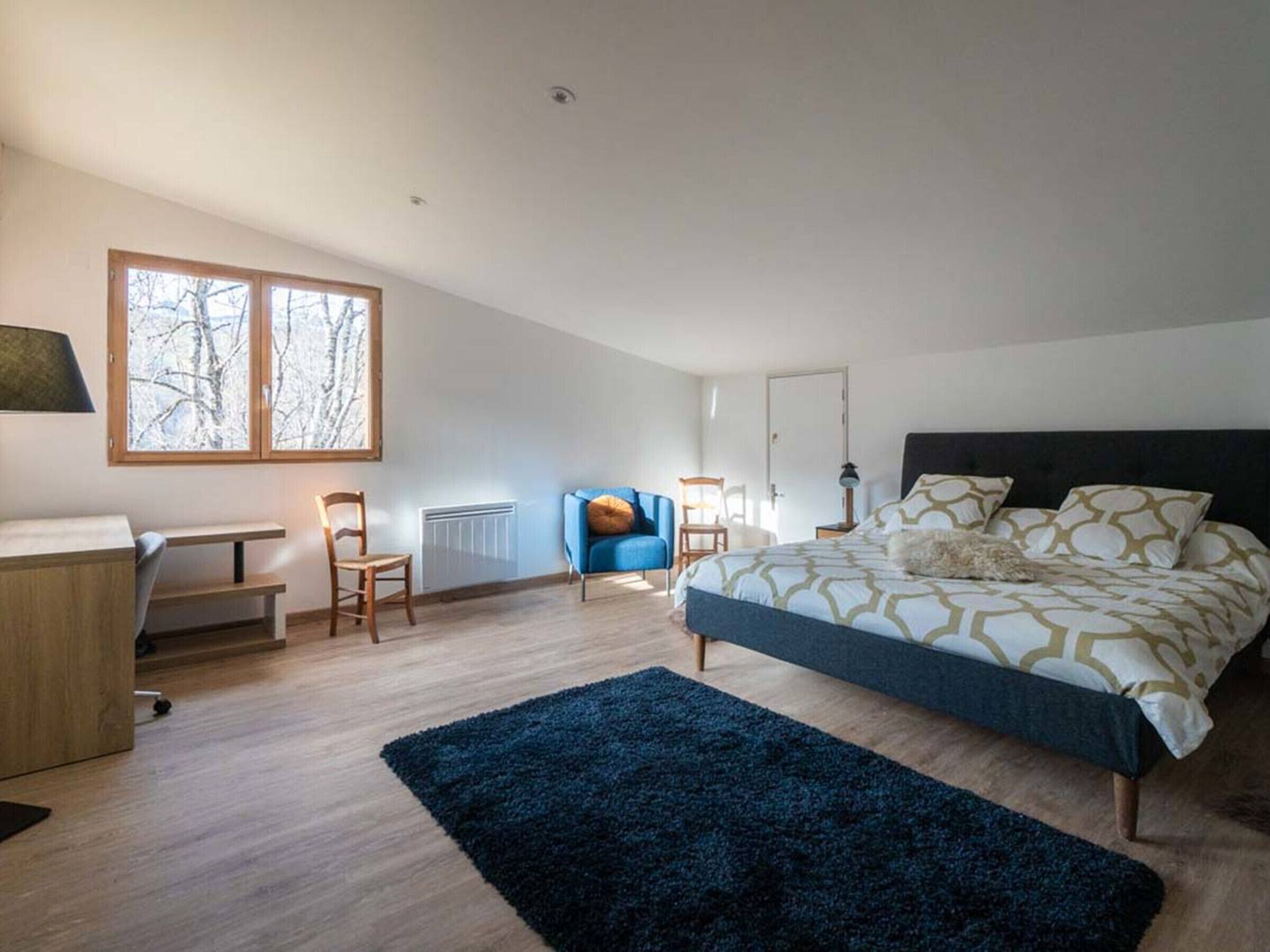 Un dormitorio moderno con una cama grande, un escritorio y una silla.