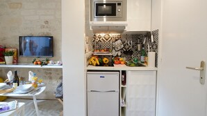 Eine kompakte Küche mit Mikrowelle, Kühlschrank und einer kleinen Essecke mit Tisch und Stühlen.