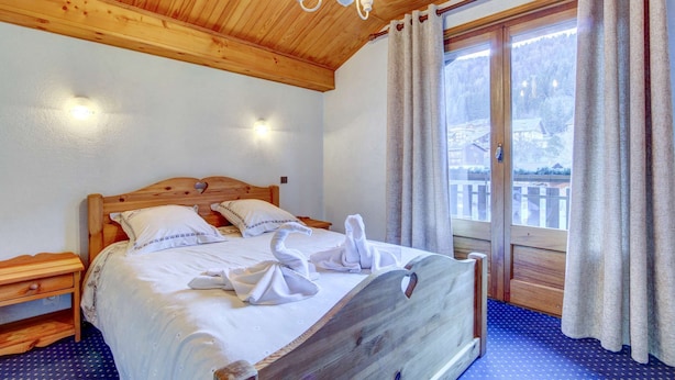 Una cama con estructura de madera, ropa de cama y toallas blancas dispuestas sobre ella.