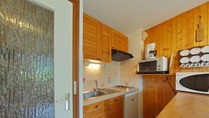 A compact kitchen with wooden cabinets, a sink, a stove, a dishwasher, and a microwave. - Studio with Terrace and Ski Locker - Le Grand-Bornand (Le Grand-Bornand)