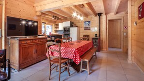 A wooden interior with a dining area, kitchen, and a television. - Griotte: Beautiful chalet in the center of Morzine (MORZINE)