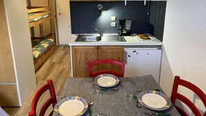 Une cuisine compacte équipée d’un four à micro-ondes, d’un évier et d’un réfrigérateur. On y trouve une table à manger, mise avec des assiettes et des couverts.