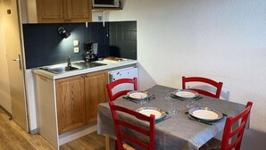 Une cuisine compacte dotée de meubles en bois, d’un four à micro-ondes, d’une machine à café et d’une table à manger pour quatre personnes.