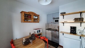 A compact kitchen with a wooden table, a microwave, a stove, and a small refrigerator.