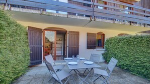 An outdoor patio with a table set for four, surrounded by chairs, and a wooden fence enclosing the area.
