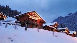 Une rangée de chalets en bois dotés de balcons, se dressant sur fond de montagnes enneigées.