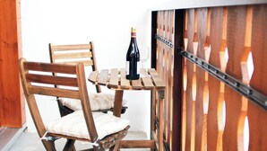 Une table de salle à manger en bois, avec des chaises, une bouteille de vin et un verre.