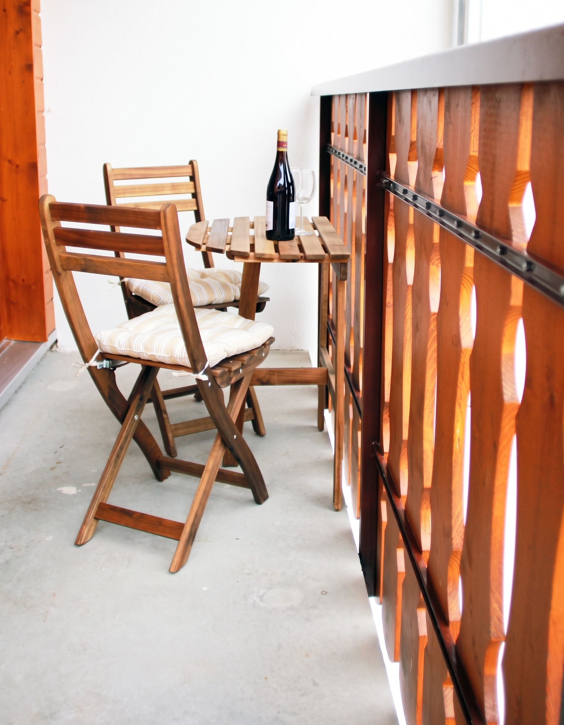 Ein Holztisch mit Stühlen, einer Weinflasche und einem Glas darauf.