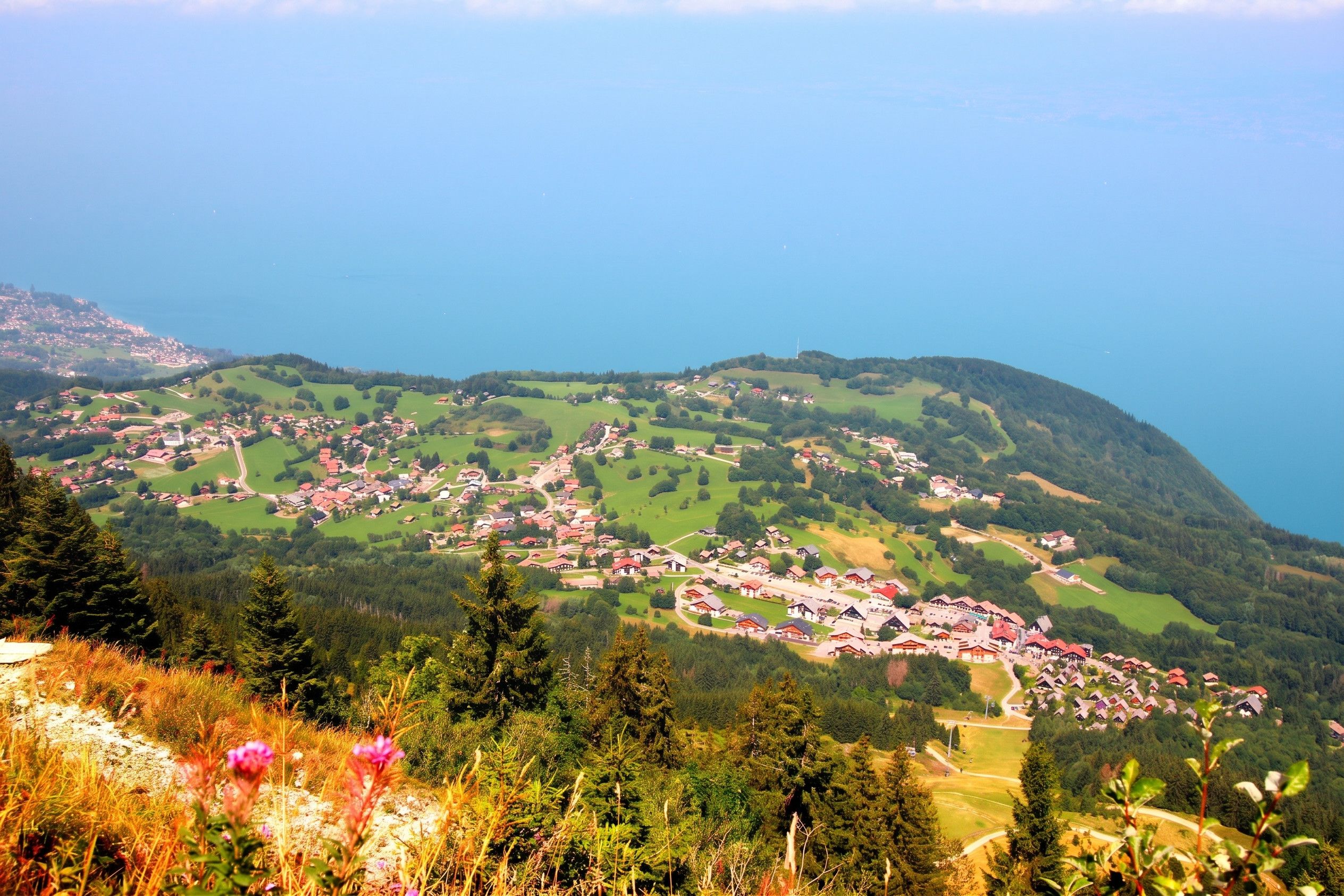 A mountainous village with houses and a body of water in the background.