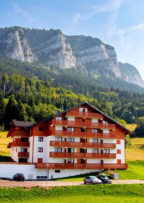 Un edificio de varios pisos con balcones, con montañas al fondo.