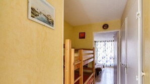 A narrow hallway with bunk beds on the left, a door on the right, and a window with curtains at the end. - Studio cabin in Esquièze-Sère for 6 with balcony, mountain view and parking (Esquièze-Sère)