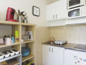 Uma cozinha com micro-ondas, cafeteira e pia.