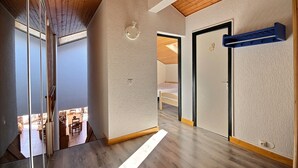 A modern interior with a wooden ceiling, a hallway leading to a bedroom, and a visible bathroom.