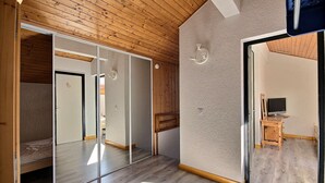 A room with wooden ceiling and walls, a large mirror, and a wooden desk with a computer.