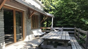 Un'area esterna con un muretto in legno, alberi e un tavolo da picnic con panche.