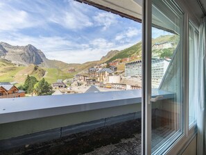 Camera d'albergo con vista su una cittadina montana e un edificio dotato di numerosi balconi.