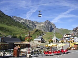 A mountain town with a cable car, outdoor seating, and a view of a mountain.