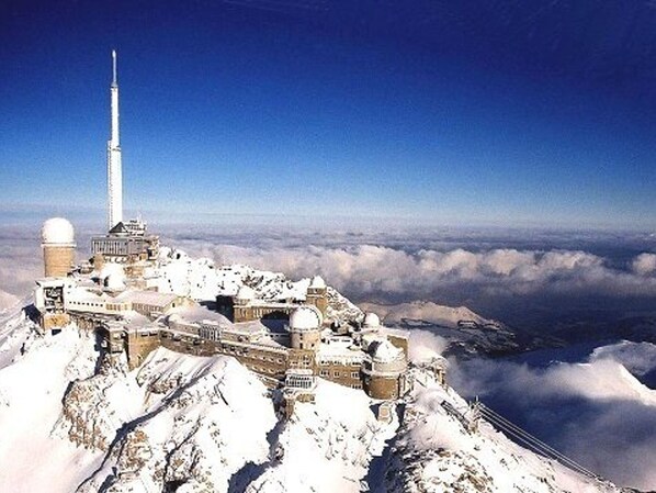 A snow-covered mountain with a large observatory and a tall tower.