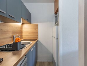 Una cucina compatta con lavandino, scolapiatti e frigorifero.