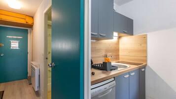 A compact kitchen with grey cabinets, a wooden countertop, and a dishwasher.