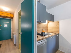 Una cucina compatta con mobili grigi, un piano di lavoro in legno e una lavastoviglie.