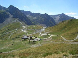 A mountainous landscape with winding roads and a small building with a sloped roof.