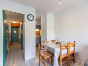 A dining area with a table and chairs, a clock on the wall, and a kitchen in the background. - Studio cabin for 5 with balcony in La Mongie - Pets allowed (La Mongie)