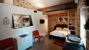 A bedroom with a bunk bed, a desk with a chair, a mirror, and a stone wall. - Melko Kivimökki (Puget-sur-Argens)