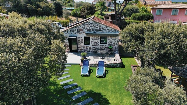 A stone house with a stone roof, a small patio with two sun loungers, and a well-maintained lawn. - Melko Kivimökki (Puget-sur-Argens)