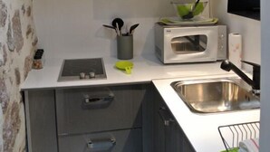A compact kitchen with grey cabinets, a microwave, a sink, and a dish rack. - Melko Kivimökki (Puget-sur-Argens)