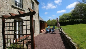 A stone building with a gravel patio, outdoor seating, and a pergola.