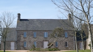 A stone building with a central entrance, multiple windows, and a sloped roof.