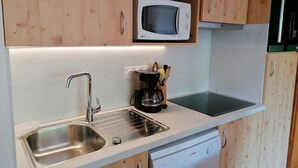Una cocina moderna con armarios de madera, un lavamanos de acero inoxidable, un lavavajillas Bosch y un microondas LG.