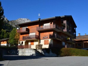 Ein mehrstöckiges Hotel mit Balkonen, einem Schild mit der Aufschrift 'La Basserie' und einem Berg im Hintergrund.