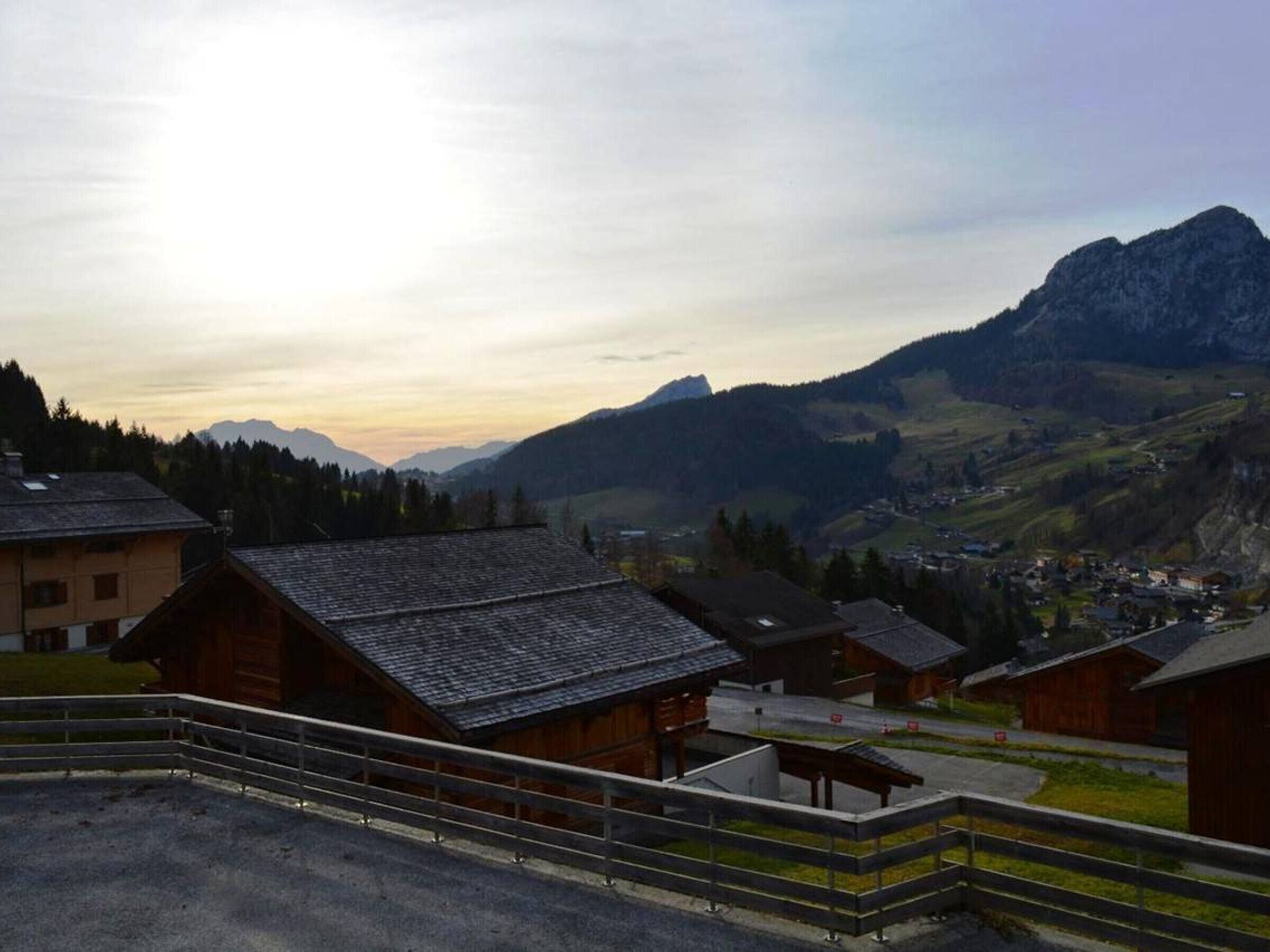 A mountainous village with traditional wooden houses, a clear sky, and distant mountains.