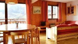 Una habitación acogedora con paredes de madera, una mesa de comedor con sillas, un sofá y un televisor.